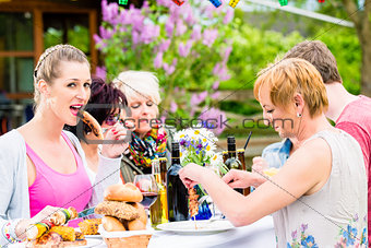 Woman eating grilled sausage on bbq party