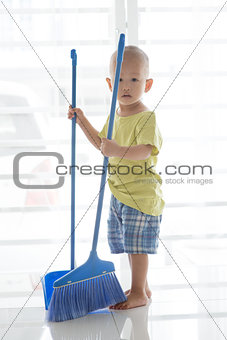 Young child sweeping floor