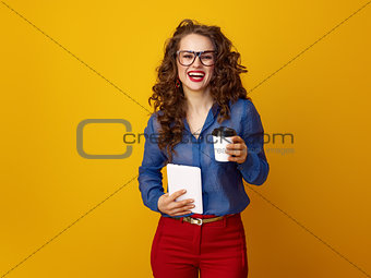 woman against yellow background with coffee cup and tablet PC