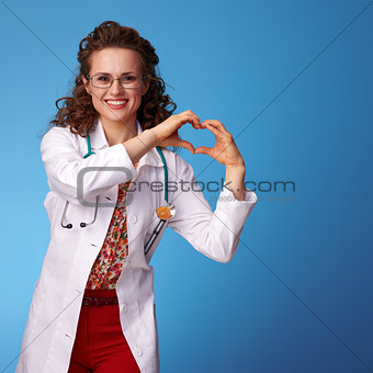 smiling paediatrist doctor showing heart shaped hands on blue