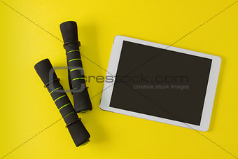 Sport flat lay composition tablet and black dumbbells
