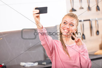 Smiling woman giving V-sign posing for a selfie