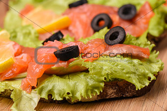 Sandwiches with red fish, lettuce, lemon and olives