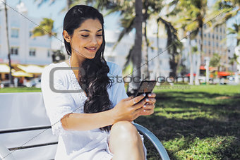 Confident stylish girl using phone in park