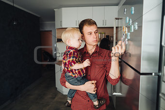 Dad and little son in the kitchen by the fridge
