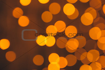 many blurred small electric bulbs on a wall. Yellow blurred lights. Wall of Christmas lights
