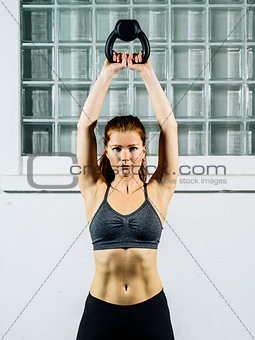 Young redhead woman exercising with a kettlebell