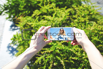 portrait of a young attractive woman using mobile phone on the blue sky background