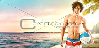 Beautiful boy with a ball at the beach at sunset. Relaxation and fun concept
