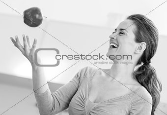 Young woman throwing apple in kitchen