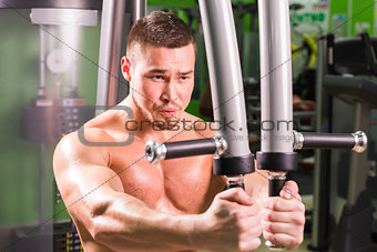 Mixed race man is working out on butterfly machine in gym