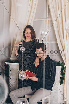 guy and girl reading a book at Christmas by the fireplace