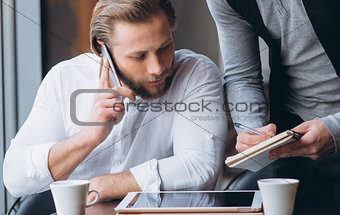 Two businessmen discussing work and using tablet