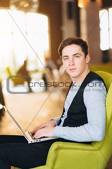 Young man with pc computer sits in a comfortable chair