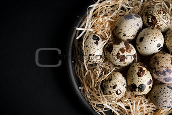 some quail eggs in a black ceramic bowl