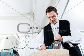 Handyman working at marble stone with disc grinder
