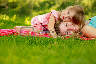 mother with her little daughter lie on the grass