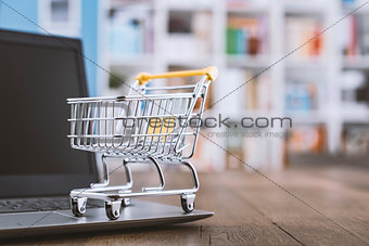 Miniature shopping cart and laptop on a desk