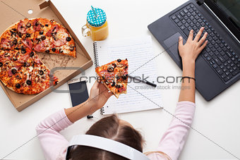 Young teenager girl working on a project while eating pizza - to