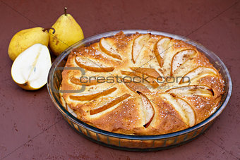 Pie with ripe pears in a glass dish. View from above topview