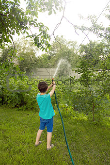 Boy playing with a sprinkler in the garden