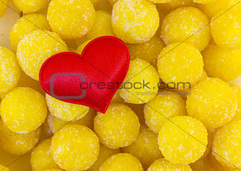 symbol of love family red heart cloth on a background of candied yellow candy balls sweet. base postcard day valentine