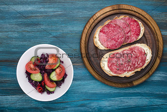 plate of sandwiches with salami and salad