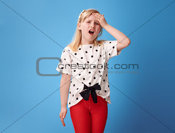 sad modern child in red pants on blue with headache