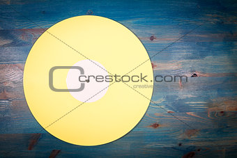 Yellow color vinyl record on blue wooden background
