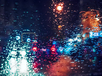 Blurred light traffic lights bokeh with rain drops on glass