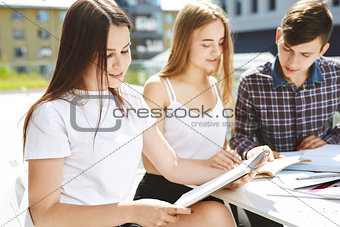 the guy student explains to the girls something and shows in a notebook