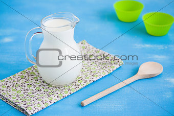 Milk jug napkin wooden spoon blue wooden background.