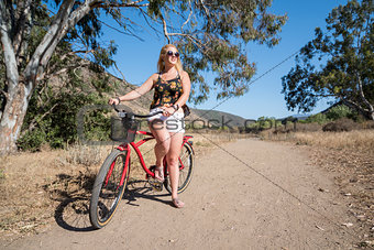 Young blond female with a beach cruiser bike on a ride outdoors