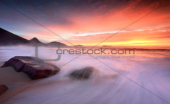 Ocean sunrise as large waves wash onto the beach
