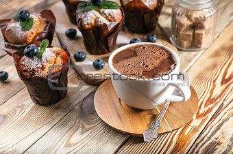 Muffins with blueberries and a cup of hot chocolate on a wooden background. homemade baking