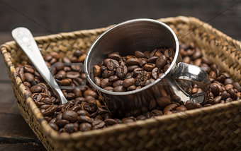 Roasted coffee beans inside a basket on a wood background