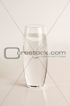 Glass of vodka on light gray background