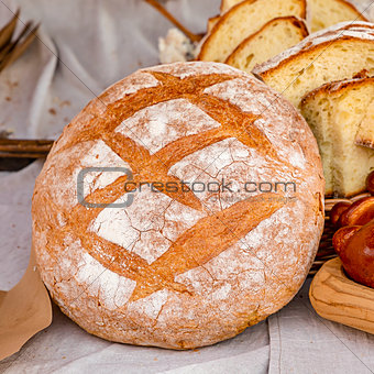 delicious fresh baked rustic bread round bun rolled up with flour on the background of chopped pieces of rustic design culinary