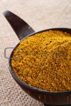 Madras Curry Powder in coconut bowl on hessian background