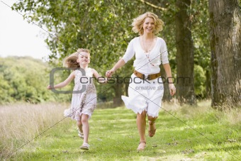 Mother and daughter running on woodland path