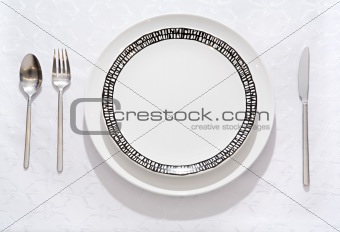 Fork, spoon, knife, empty plate on a table