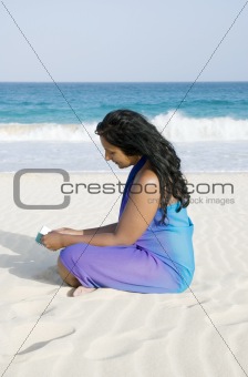 Beautiful asian girl reading on beach.