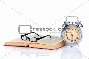 book with alarm clock and eyeglasses 