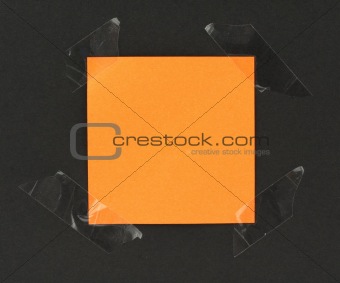orange post-it stuck to a blackboard with tape