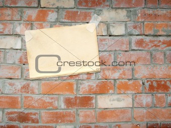 Sheet of a paper, hanging on a brick wall