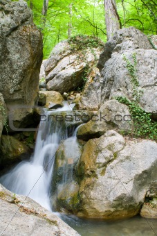 Waterfall in rocks in green relic forest