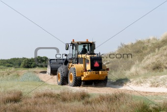 Bulldozer driving fast throw the dunes