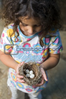 little girl holding nest with eggs