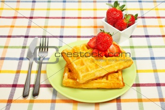 Waffles and strawberries on green plate
