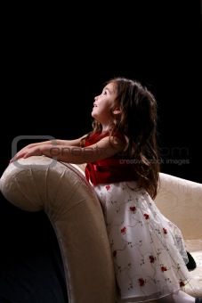 little girl kneeling on couch and looking up